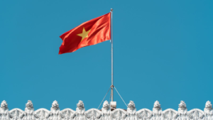 Vietnamese flag waving over an ornate white building against a clear blue sky.