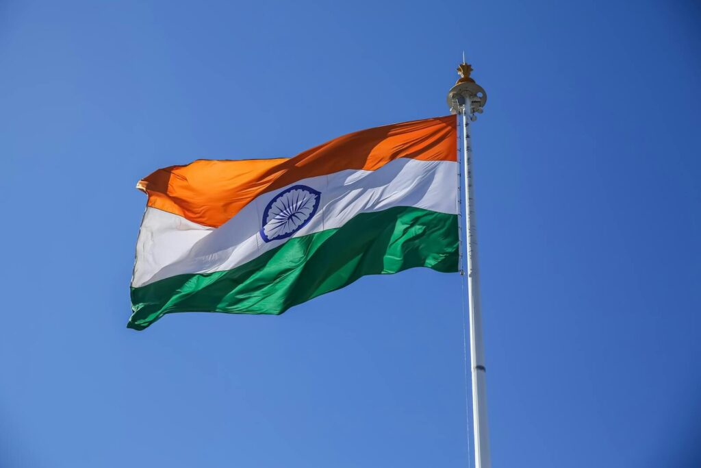 A vibrant Indian national flag waving proudly against a clear blue sky in Shimla, Himachal Pradesh.