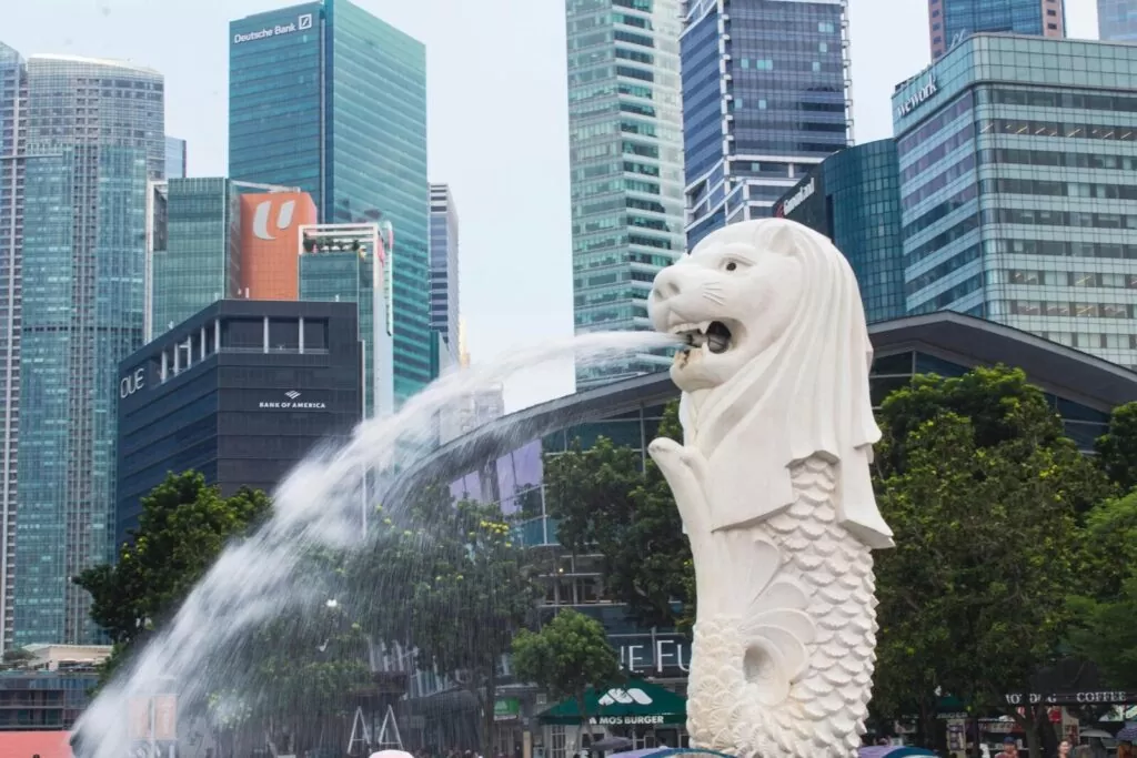 The Merlion statue with flowing water in front of Singapore's modern cityscape.